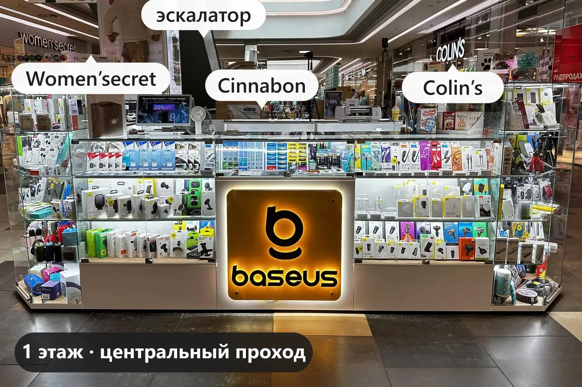 Островок с оранжевой вывеской Baseus на 1 этаже Dana Mall: за ним киоск Cinnabon и эскалатор, слева Women’secret, справа Colin’s