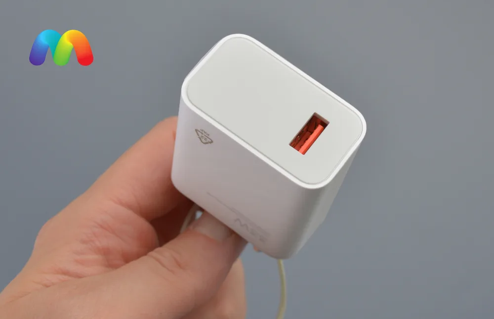Крупный план белого зарядного устройства Xiaomi на 33 Вт, которое держит в руке. Основной фокус на USB-C порте.