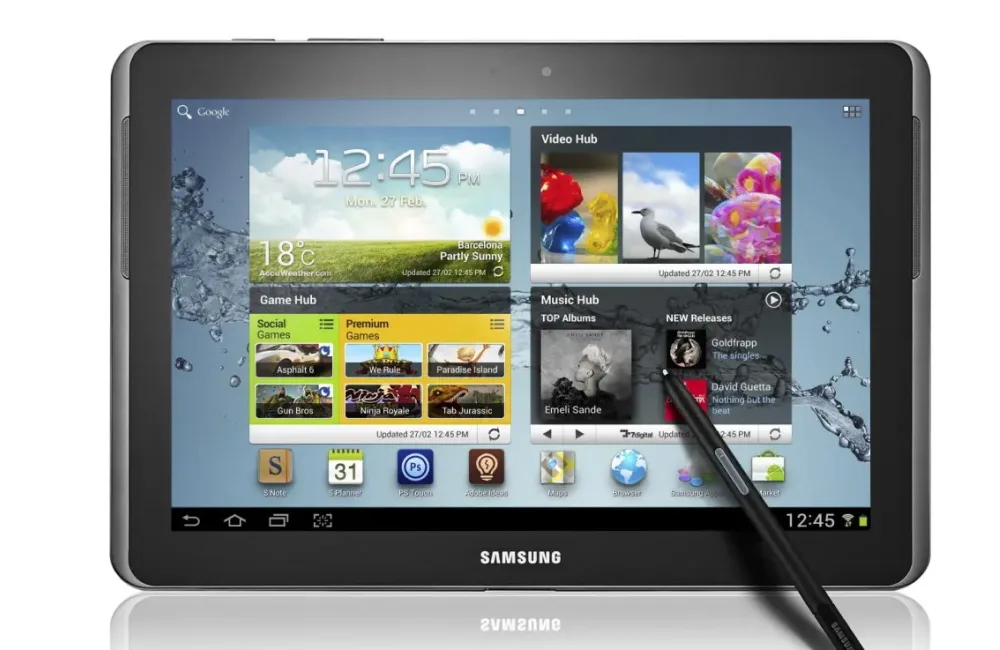 Фронтальный вид старого планшета Samsung Galaxy с темно-серым корпусом и экраном, на котором отображаются различные виджеты и иконки. На экране также виден стилус.