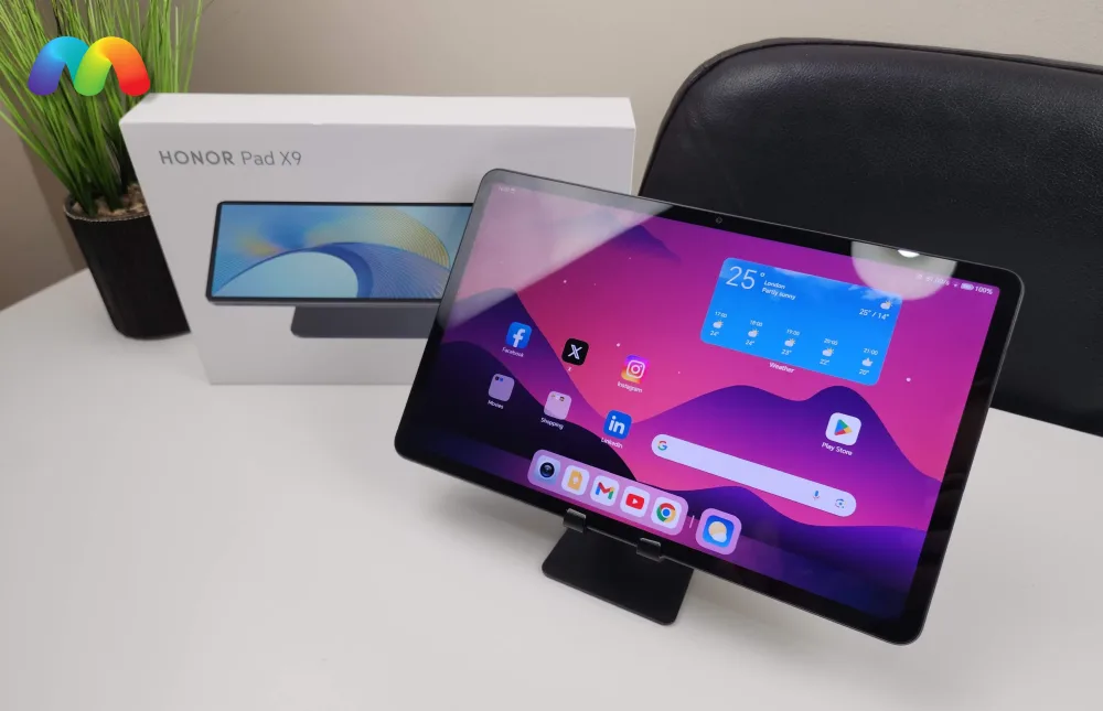 Планшет Honor Pad X9, стоящий на подставке, с коробкой на заднем плане.
