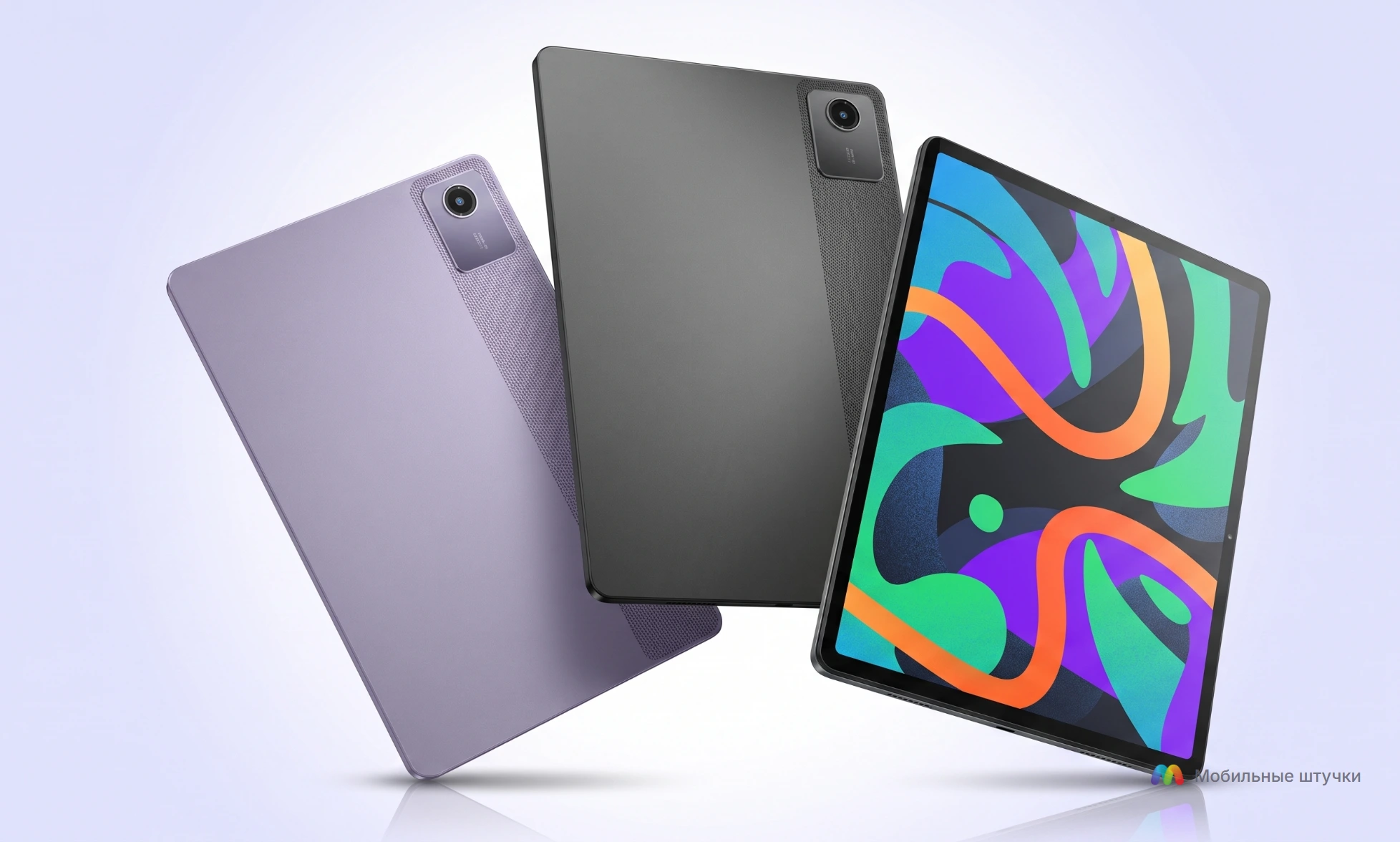 Три планшета Lenovo Xiaoxin Pad 2024, расположенные по диагонали на двухцветном (зеленый и синий) фоне. Два планшета показаны с задней стороны (один сиреневый, другой серый), третий с включенным экраном, отображающим яркий абстрактный узор. Сверху логотип "Мобильные штучки".